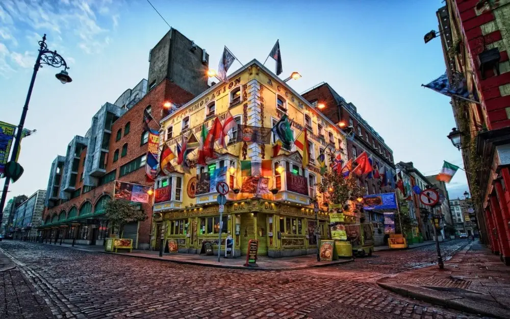 corner of a street in dublin showing a bright yellow building with lots of flags of various countries hanging from it