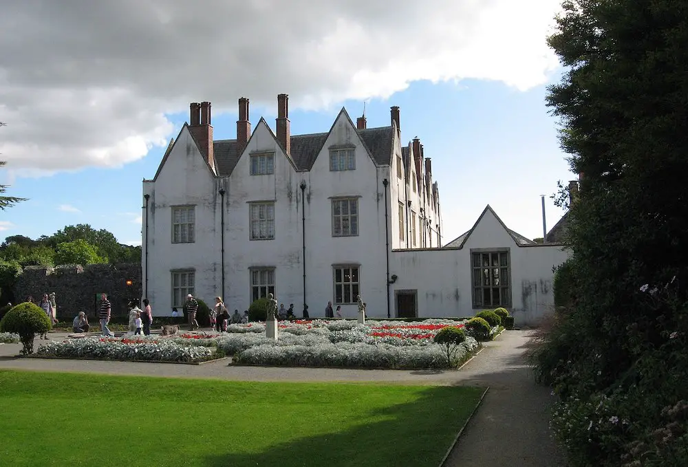 view of St Fagans Castle and lawns with people wandering the grounds