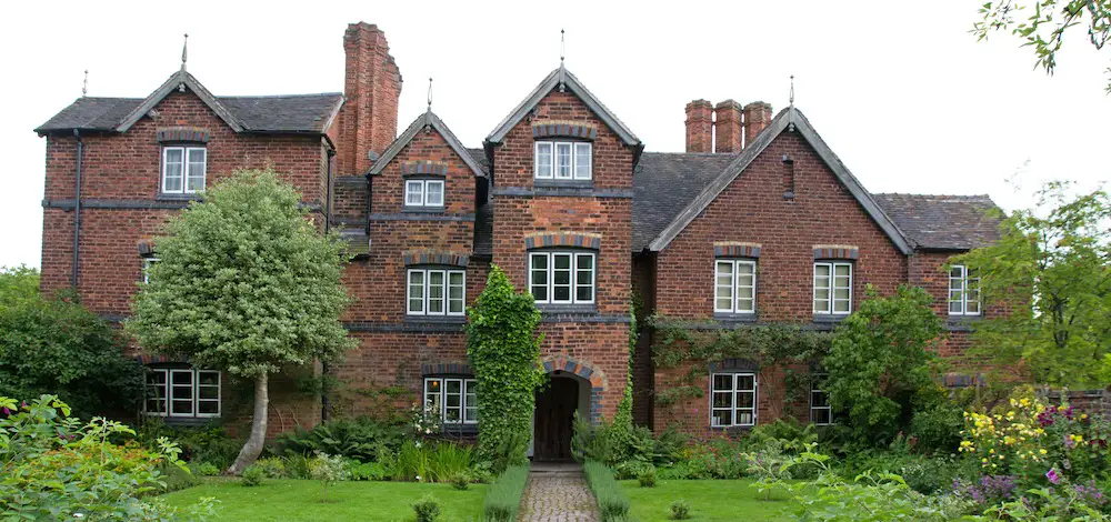 view of the front of moseley old hall with a lawn and shrubbery surroundings