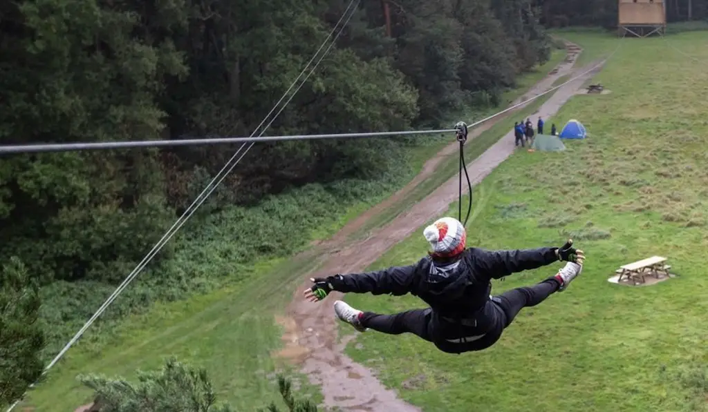 a woman swinging down a zip wire with her arms and legs spread out