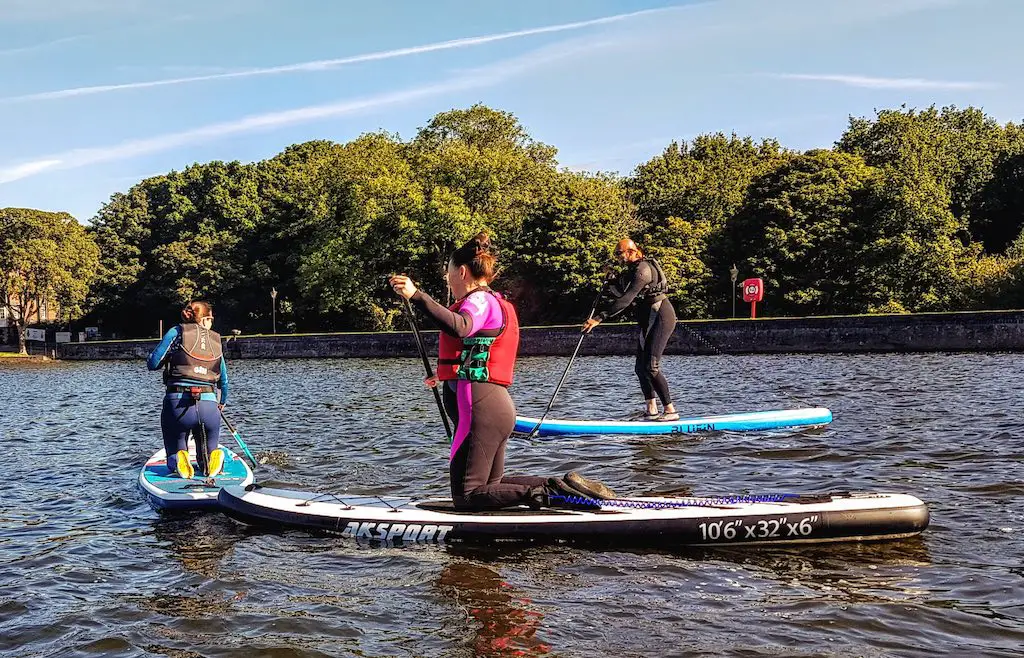 closeup view of three women paddle boarding at sutton park in england