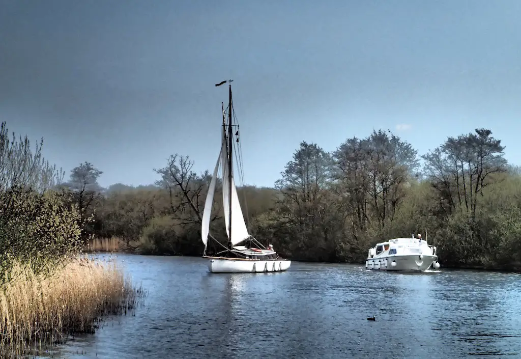 a view of the norfolk broads wetlands area with two boats on the water