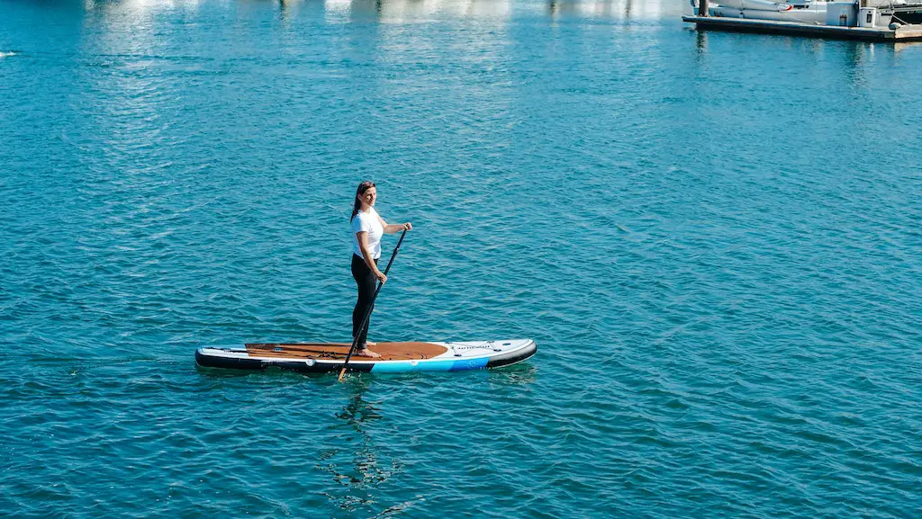 a woman paddleboarding along ladram bay, devon