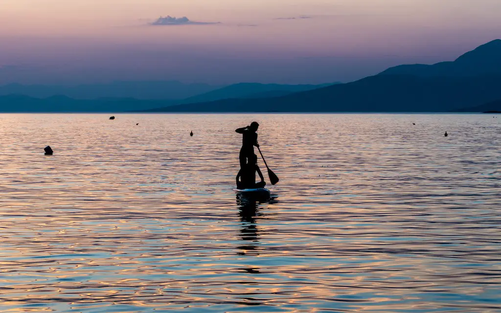 sunset view of two paddleboarders on glencoe lake, scotland