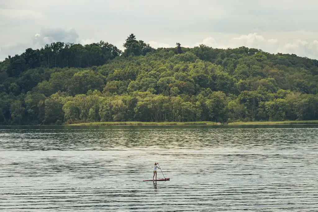 wide view of the lake at pembrokeshire national park with a woman paddleboarding along the lake