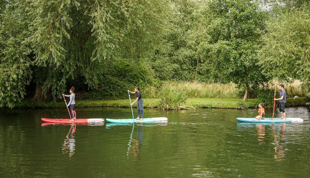 some paddleboarders paddling along the river cam in cambridge