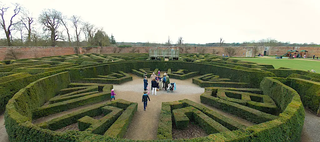 view overlooking a medium-sized, circular maze with people at the centre of the maze