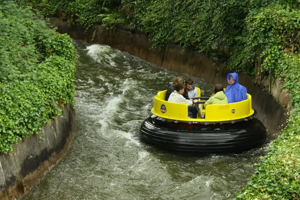 a round dinghy with some people sitting in it passing round a bend on the rapids at alton towers theme park