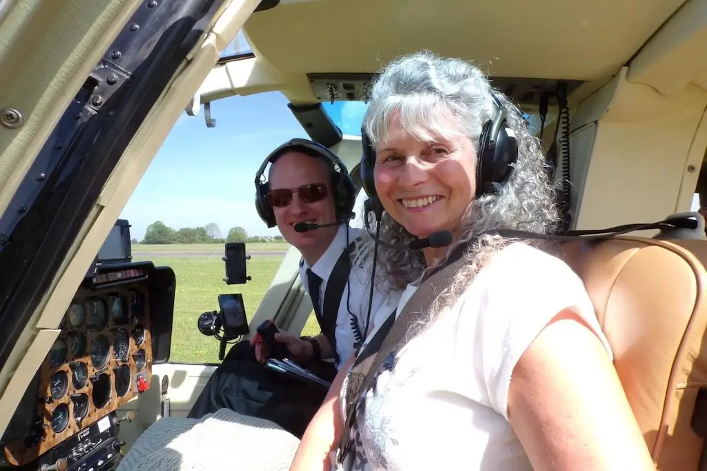 a female customer and the pilot seated at the front of helicopter smiling and posing for the photo