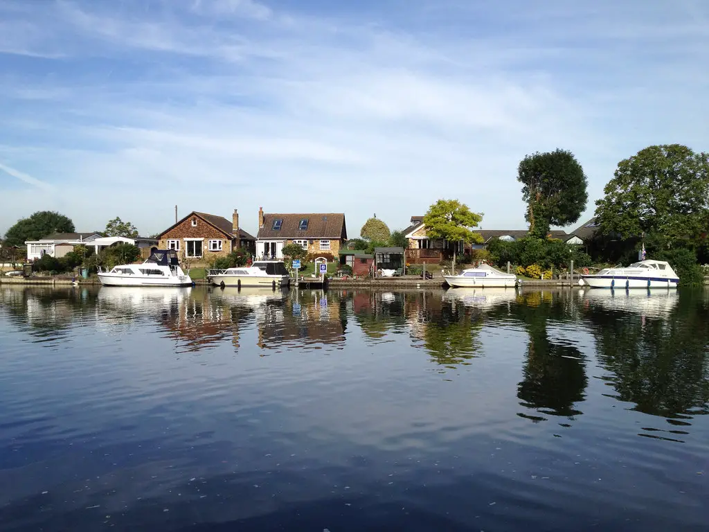 view of houses by the river with boats moored on the riverside