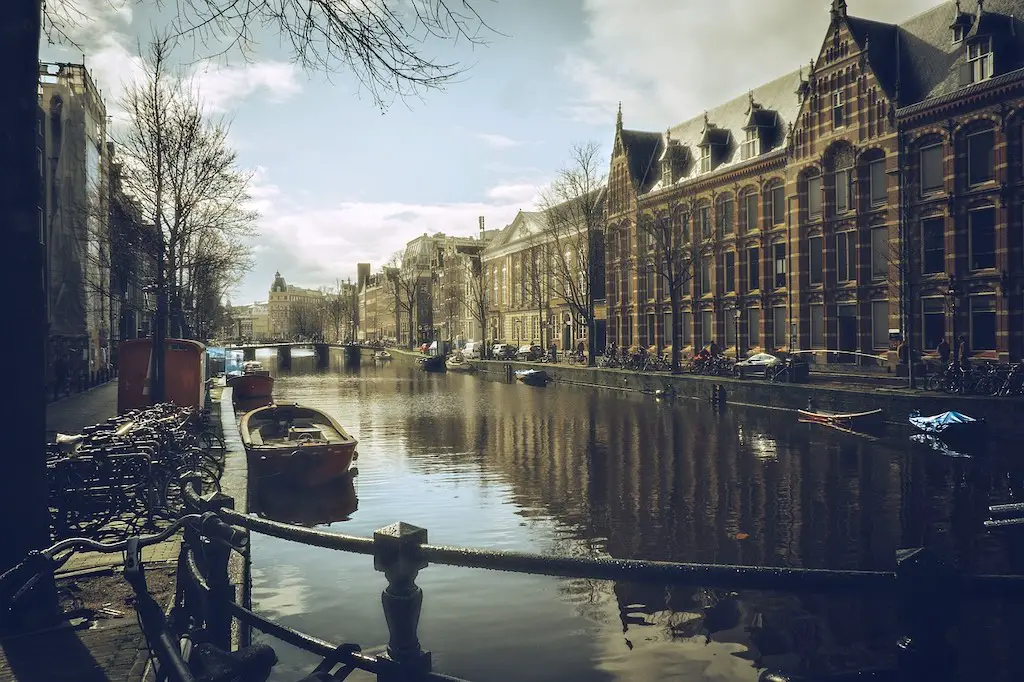 view of a calm canal lined with tall pretty buildings on both sides in amsterdam, netherlands